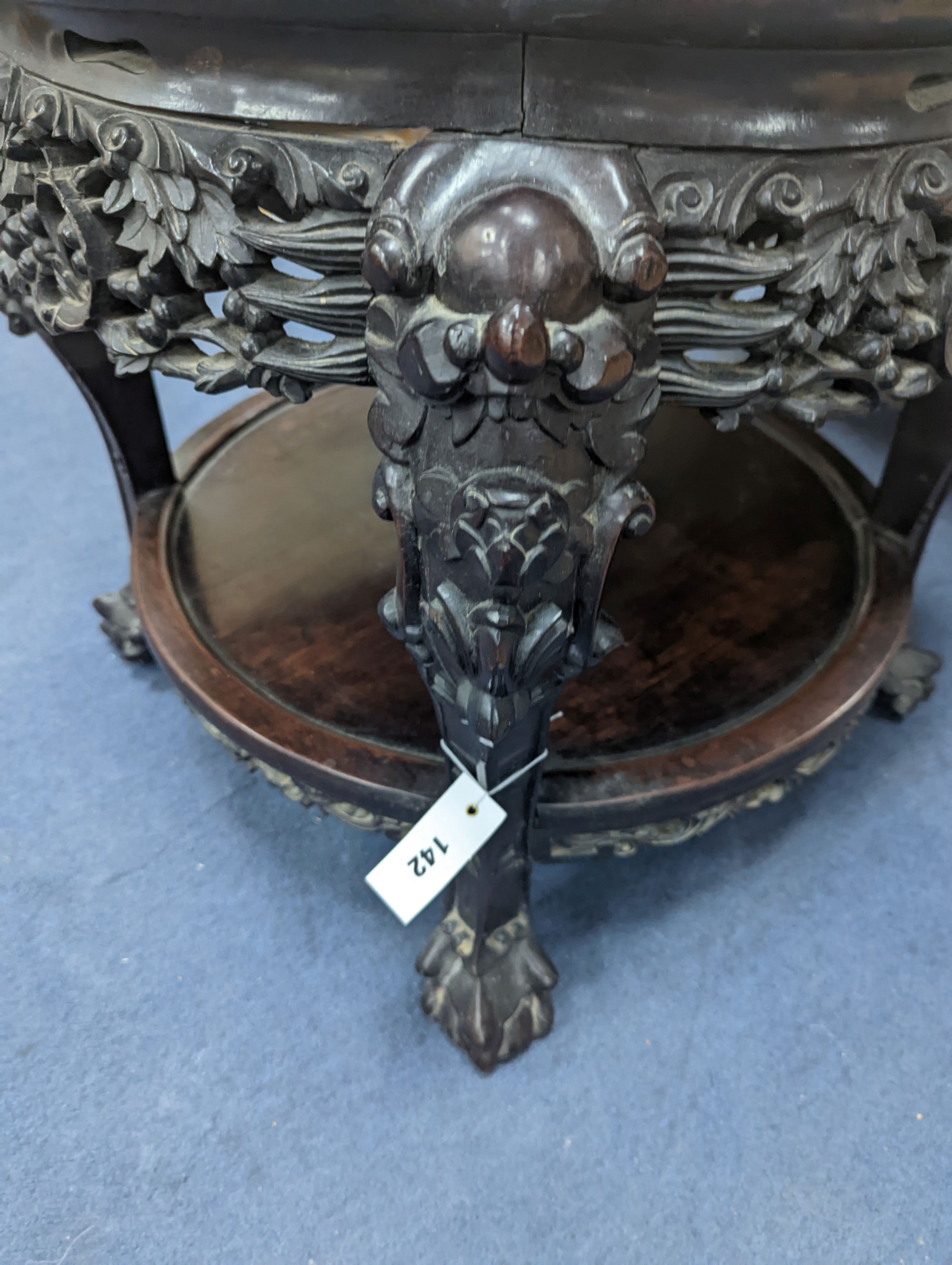 An early 20th century Chinese carved hardwood two tier table, diameter 64cm, height 56cm